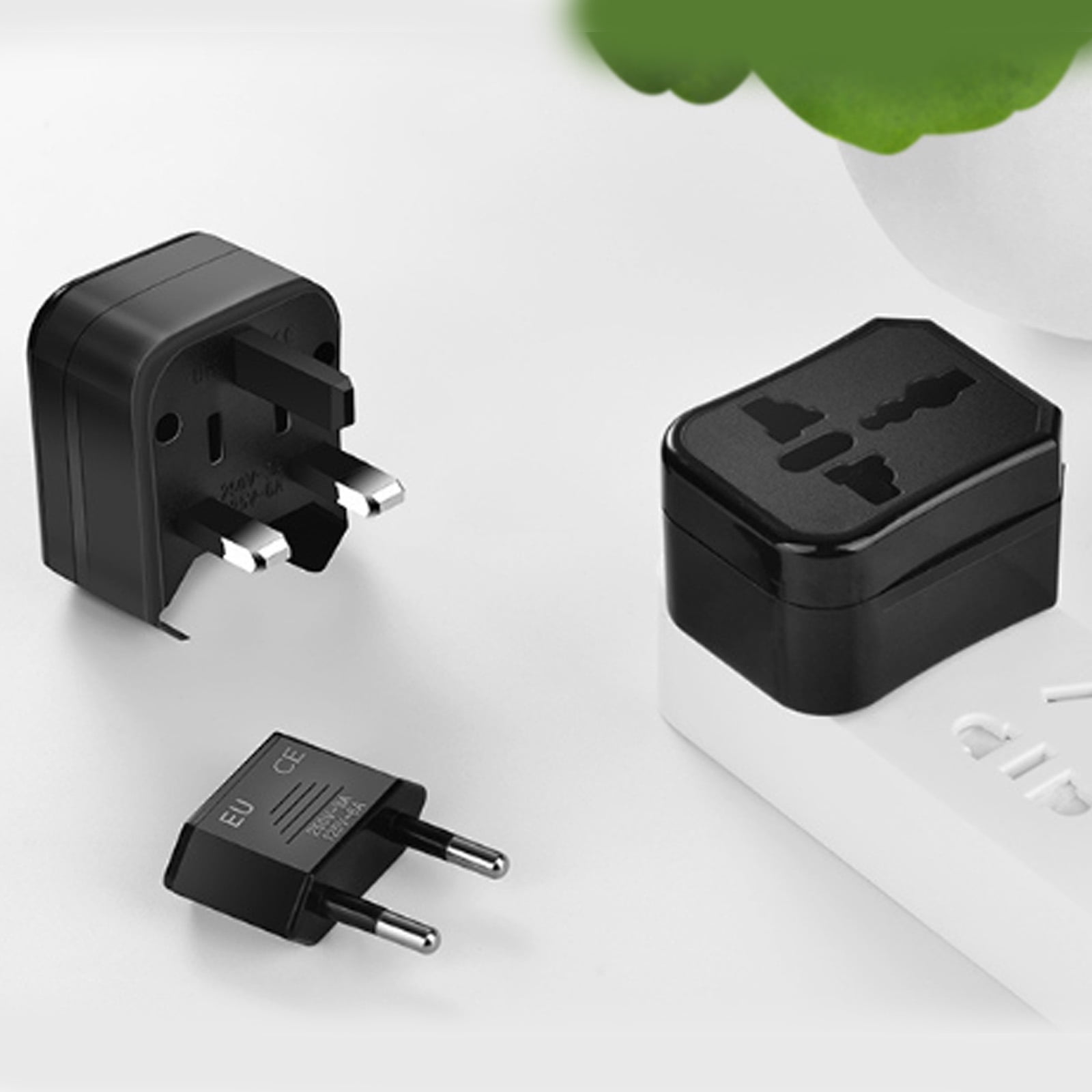 Schwarze und EU-Steckeradapter. Zwei schwarze Adapter und ein EU-Adapter auf weißer Oberfläche.