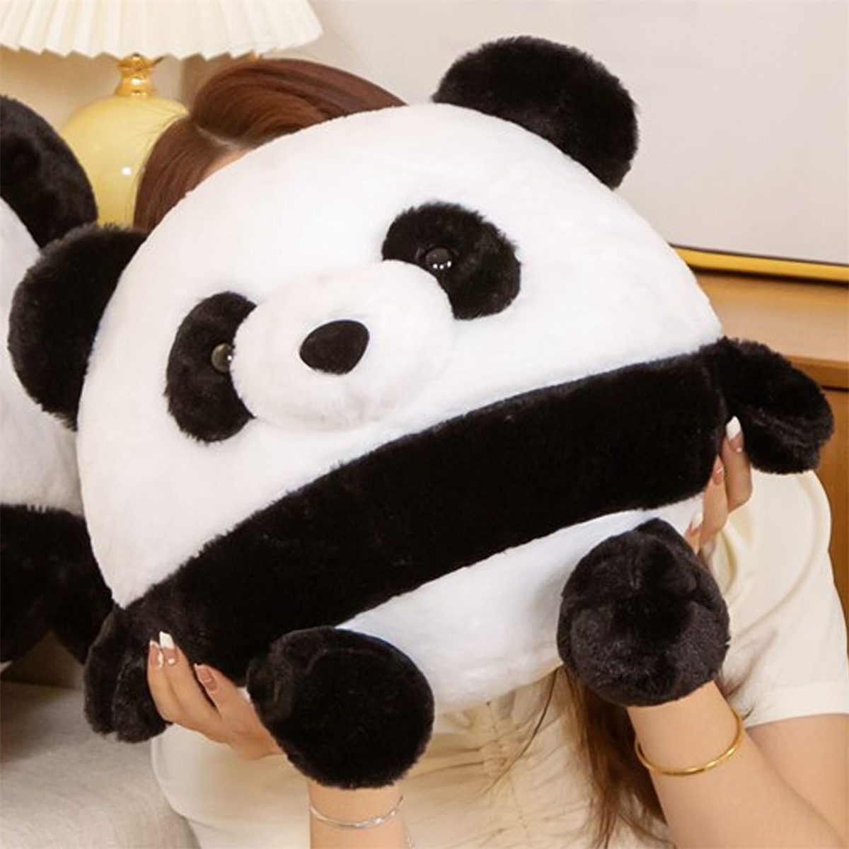 Panda-Stofftier. Es hat schwarz-weißes Fell. Eine Person hält es.