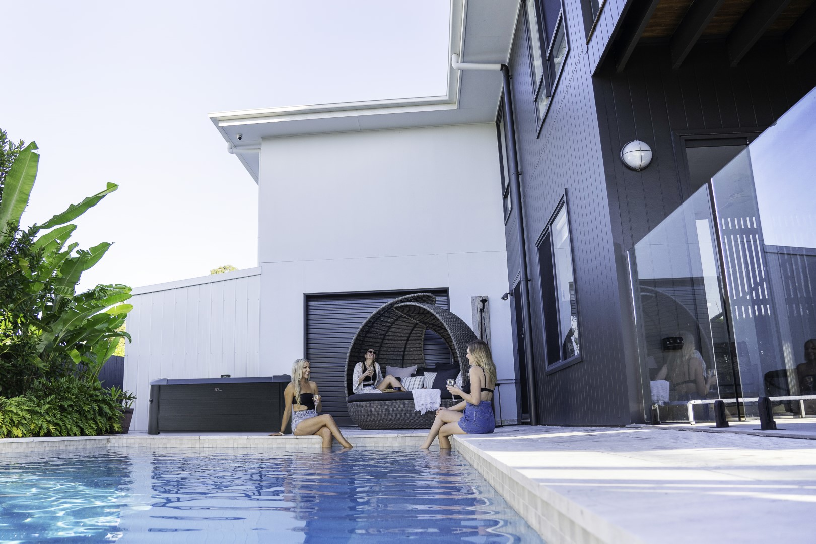 Drei Frauen in einem Pool neben einem modernen Haus mit Pool.