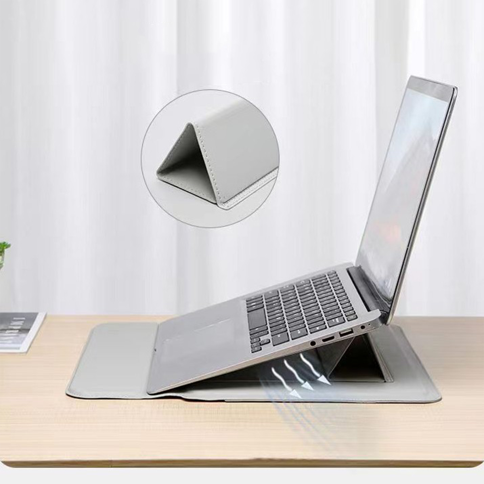 Laptop auf einem faltbaren Ständer. Der Laptop ist erhöht, Luftschlitze sichtbar, auf einer hellgrauen Oberfläche.