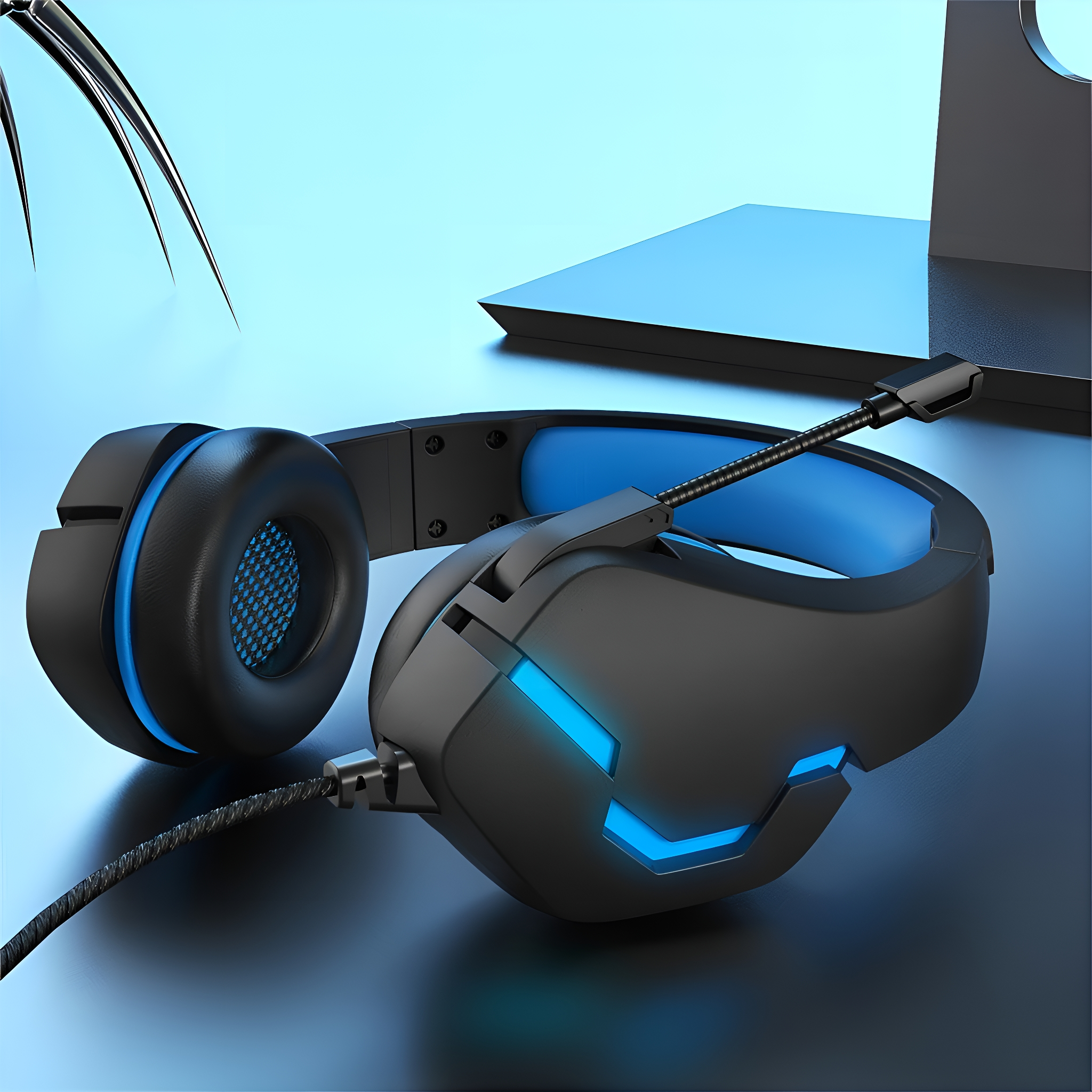 Schwarzes und blaues Gaming-Headset mit flexiblem Mikrofon, das auf einer dunklen Oberfläche mit Monitor im Hintergrund liegt.