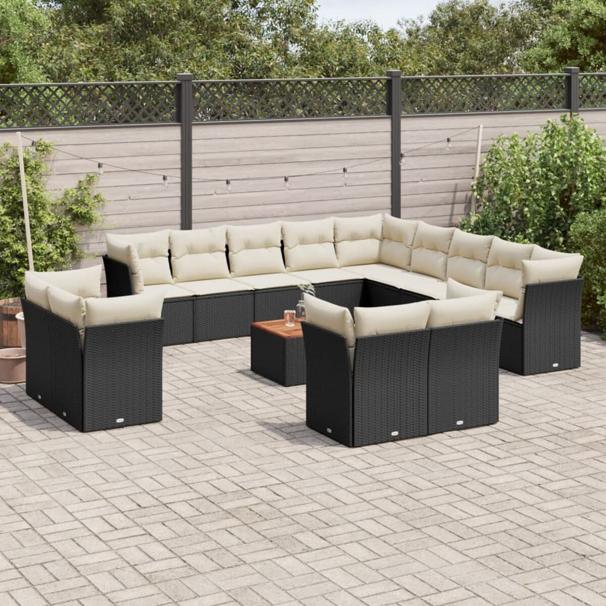 Outdoor-Terrassenmöbel-Set mit schwarzem Korbgeflecht und beigefarbenen Kissen, angeordnet in einem Garten.