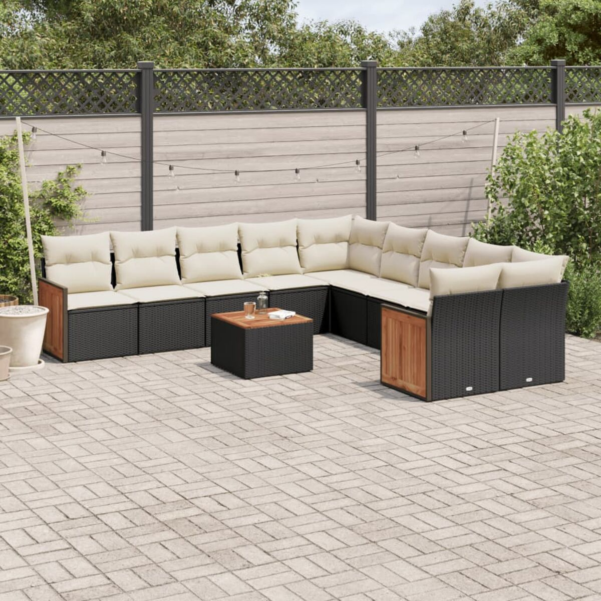 Set divano componibile da esterno con vimini nero e cuscini beige. Include un tavolino e dettagli in legno.