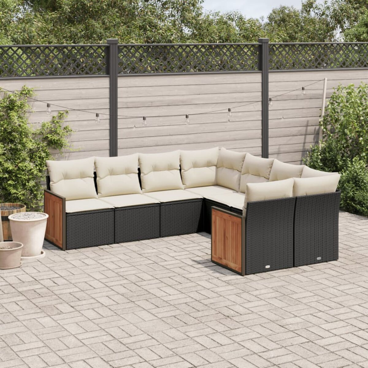Un set da patio con base in legno e cuscini beige. Lo sfondo ha una recinzione in legno e piante.
