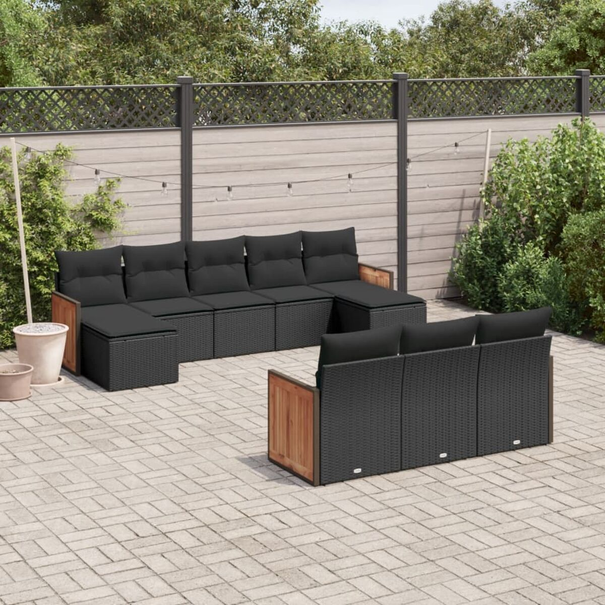Set di mobili da esterno con cuscini neri. Include un divano componibile e un divano separato, su un patio.