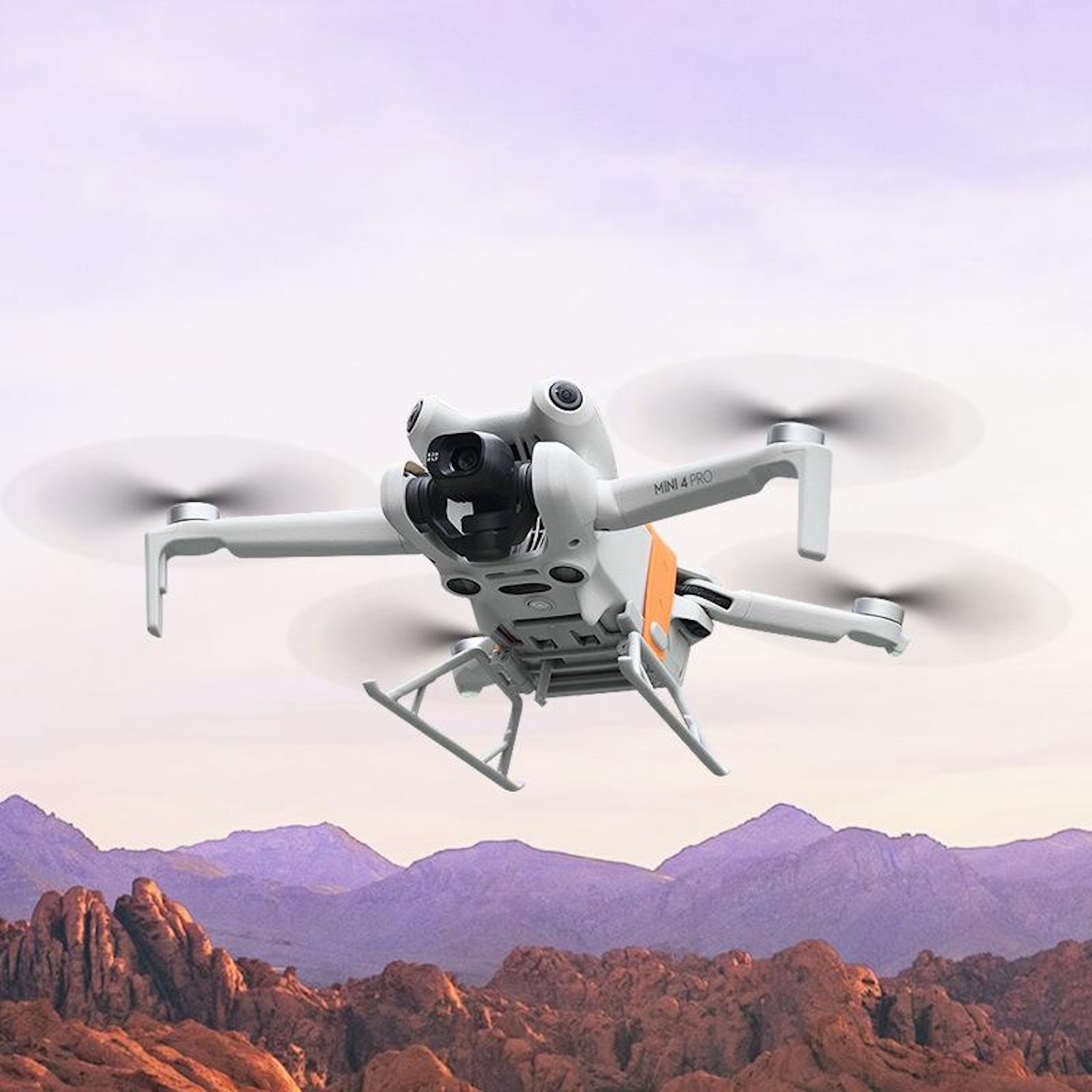 Drone bianco che vola in un cielo viola sopra una catena montuosa.