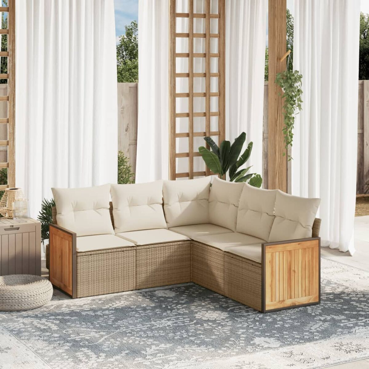 Divano a L con cuscini color crema e struttura in legno su patio con tappeto, tende bianche.
