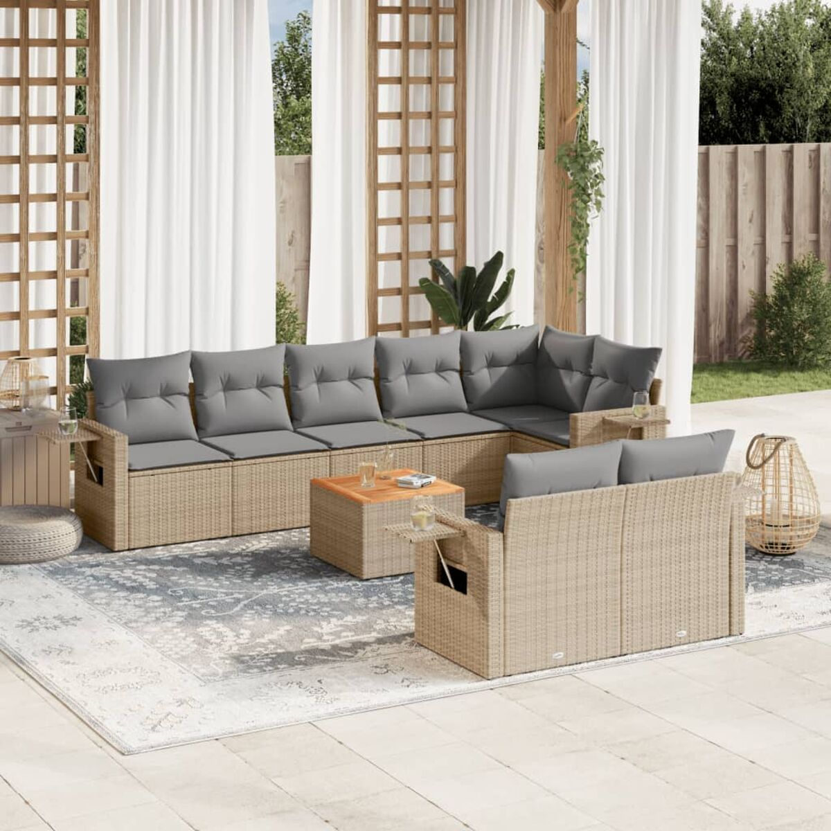 Set divani da esterno. Mobili in vimini beige, cuscini grigi. Include tavolo, tappeto e piante.