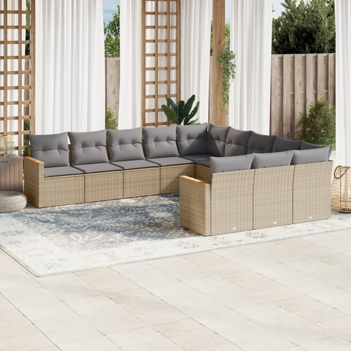 Ein beiges Outdoor-Ecksofa mit grauen Kissen auf einer Terrasse mit Vorhängen und Holzzaun.