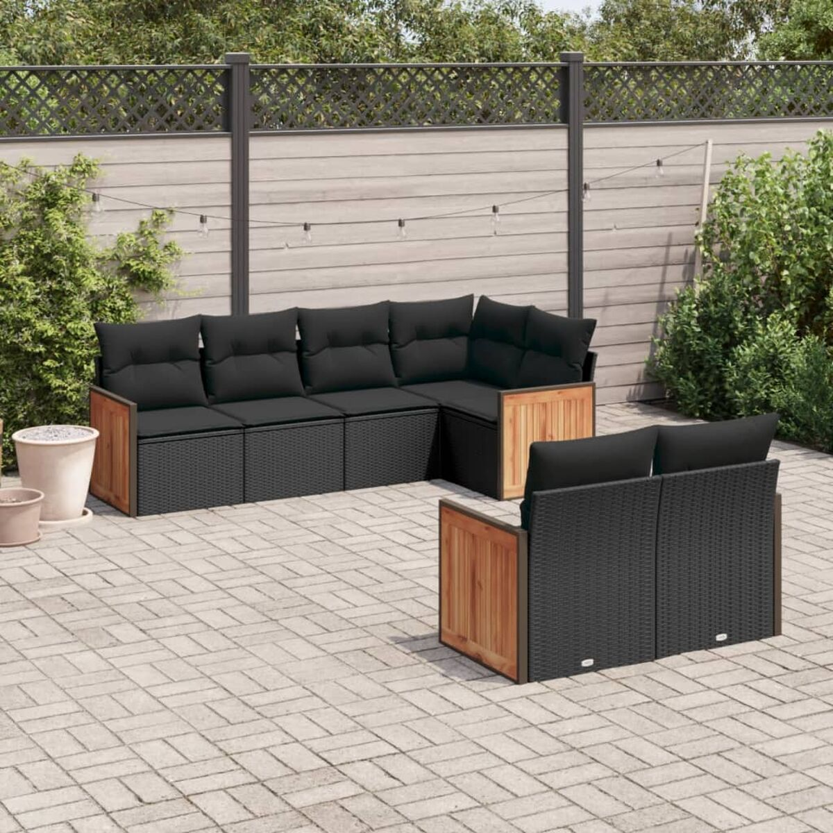 Set patio esterno con mobili in vimini neri. Include un divano angolare e un divano a due posti separato, accenti in legno.