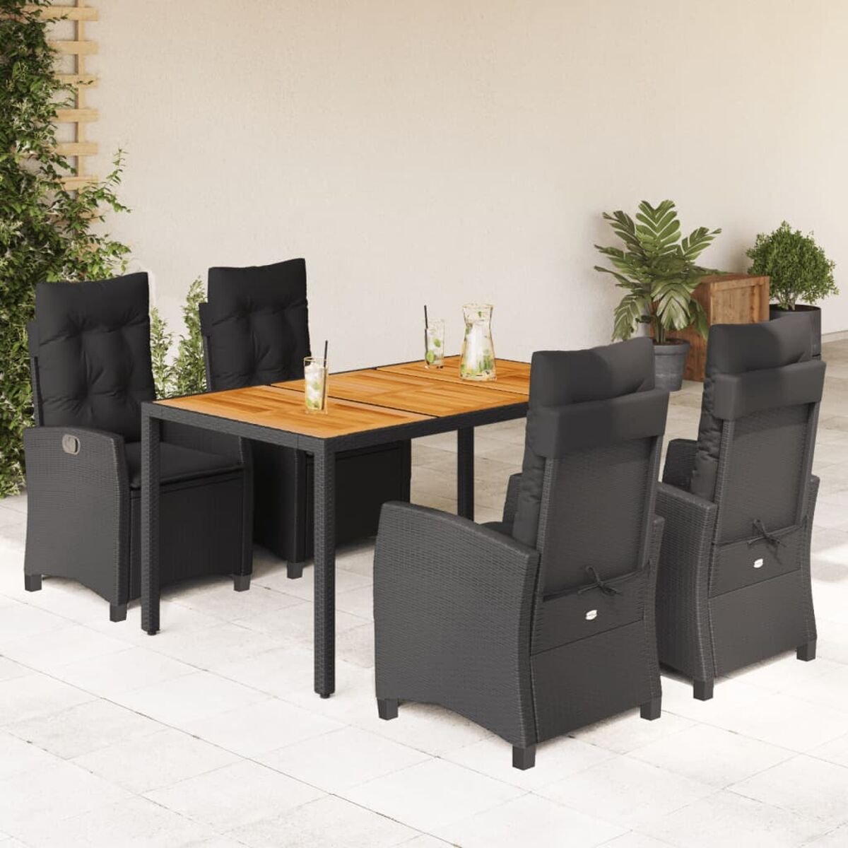 Set da pranzo all'aperto: tavolo con piano in legno, 4 sedie nere con cuscini e piante.