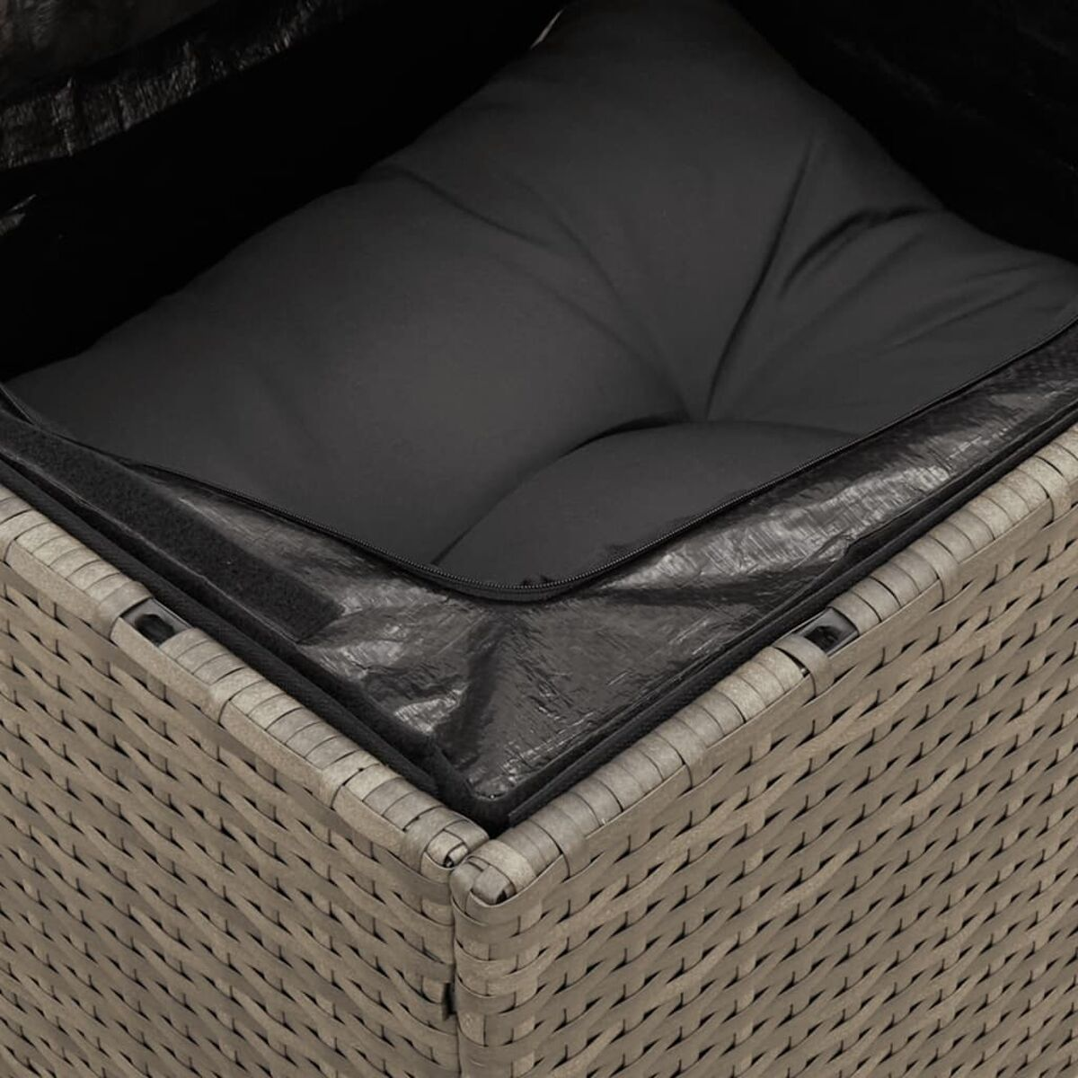 Primo piano di un cuscino per sedia grigio e in vimini intrecciato con una copertura nera con cerniera.