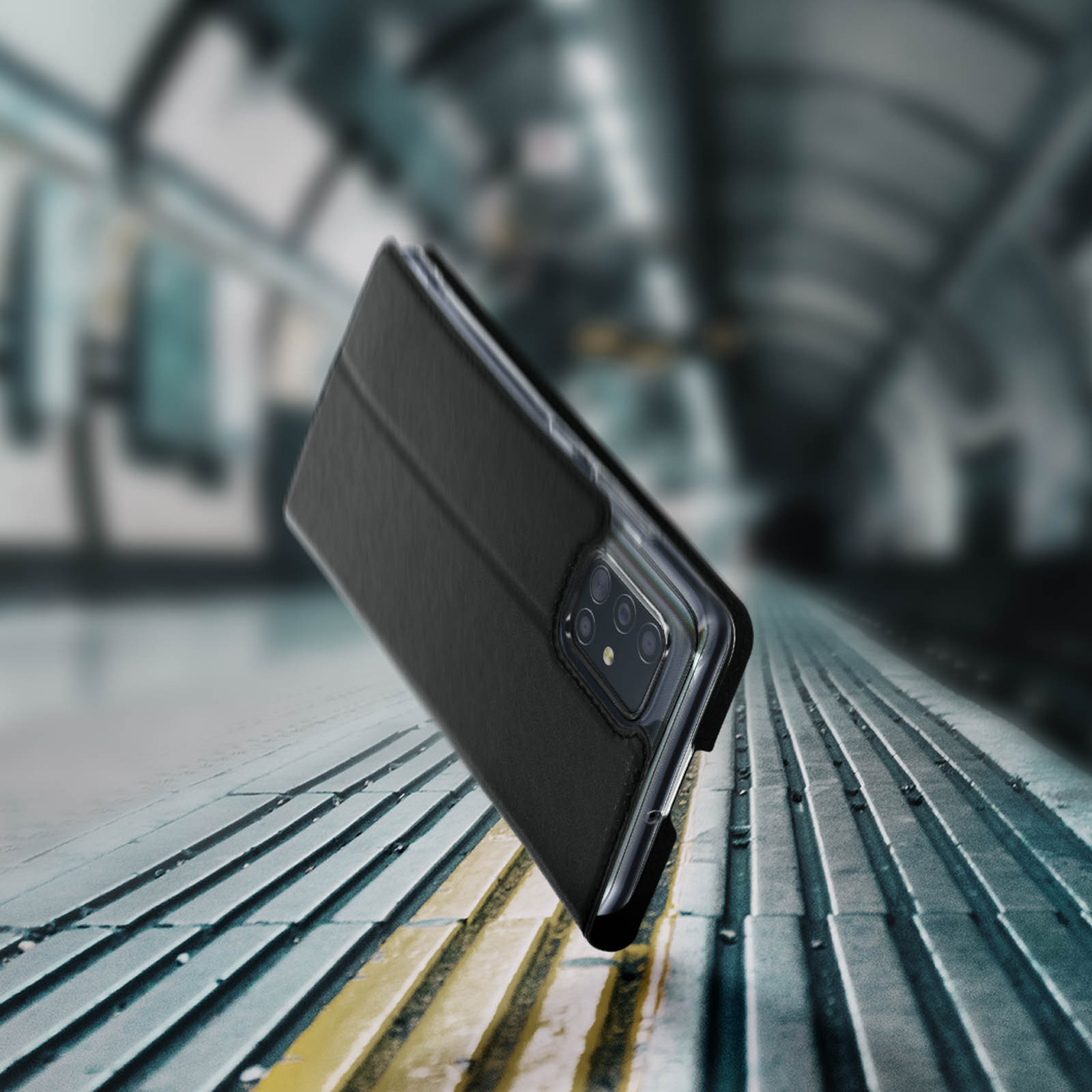 Custodia nera per telefono con telefono all'interno, su uno sfondo urbano sfocato con binari.