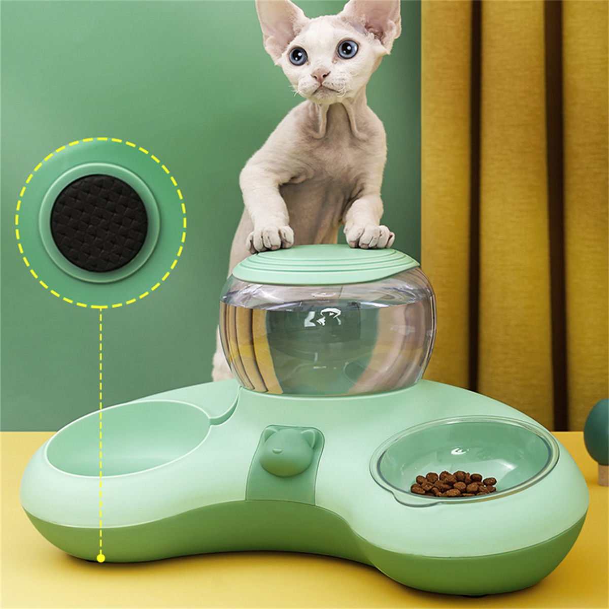 Eine Katze steht auf einem grünen Haustierfutterautomaten mit Futternäpfen und Wassernäpfen.
