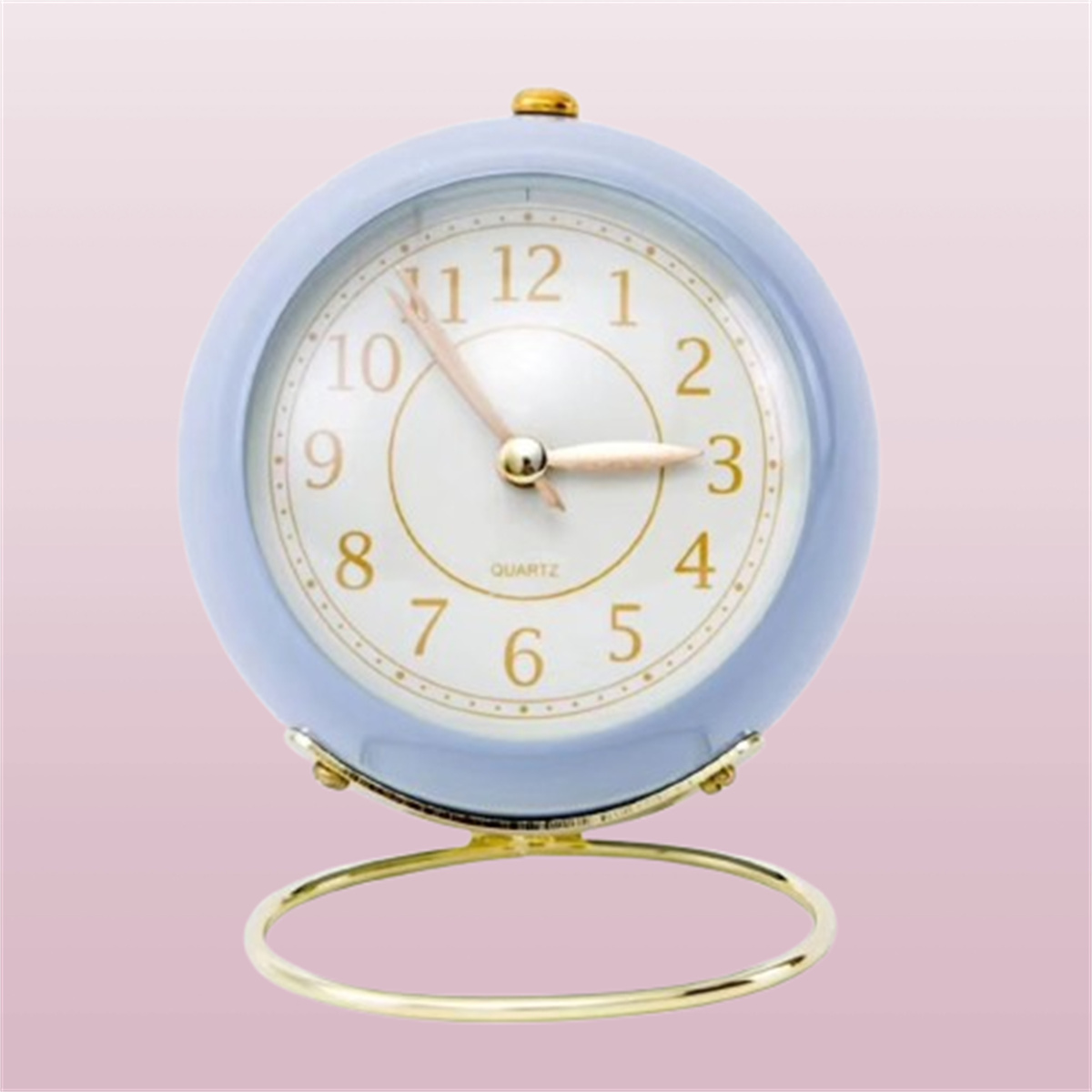 Blauer Wecker mit weißem Zifferblatt und goldenen Akzenten. Auf pinkfarbenem Hintergrund.