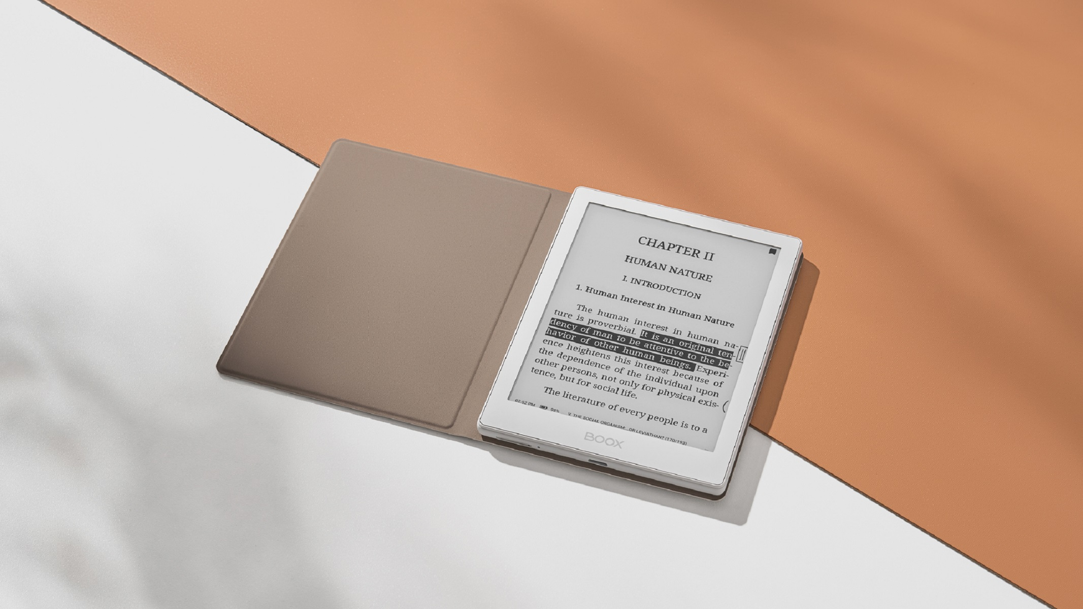 Un e-reader aperto su un tavolo, con una copertina di libro accanto.