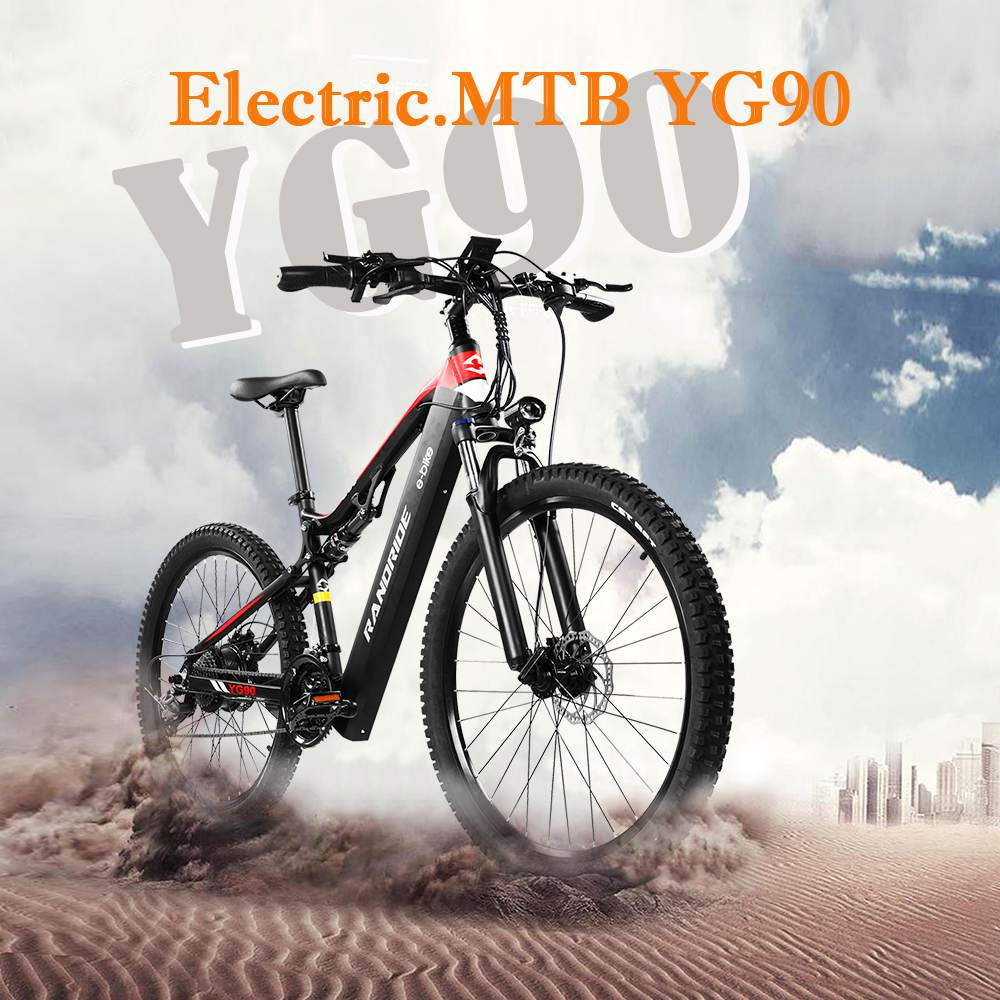 Schwarzes und rotes elektrisches Mountainbike. Das Fahrrad steht auf einer staubigen Straße mit Stadt im Hintergrund.