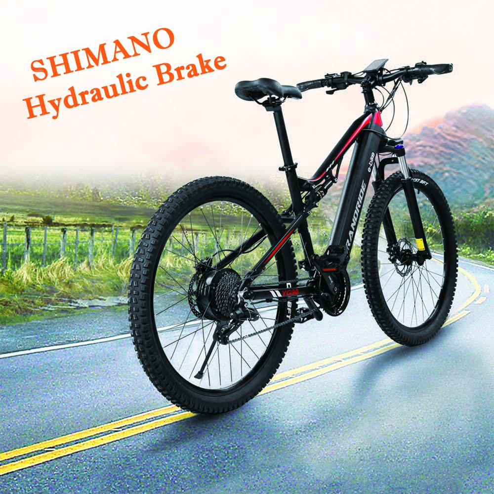 Schwarzes und rotes Elektro-Mountainbike mit hydraulischen Shimano-Bremsen, vor verschwommenem Hintergrund.