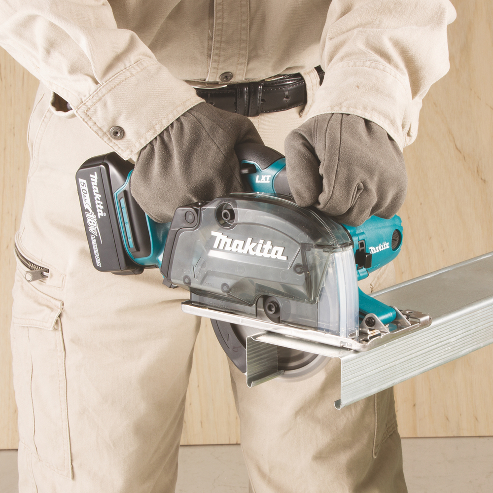 Person using a Makita power saw to cut metal. Beige pants, gray gloves.