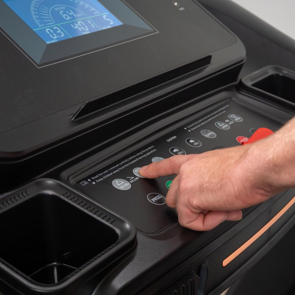 Ręka osoby naciskająca przycisk na panelu sterowania bieżni.