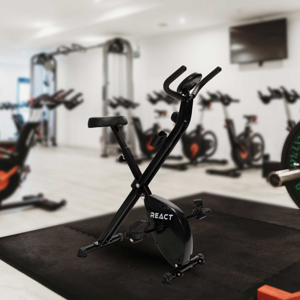 Schwarzes Trainingsrad in einem Fitnessstudio. Andere Trainingsgeräte sind im Hintergrund unscharf.