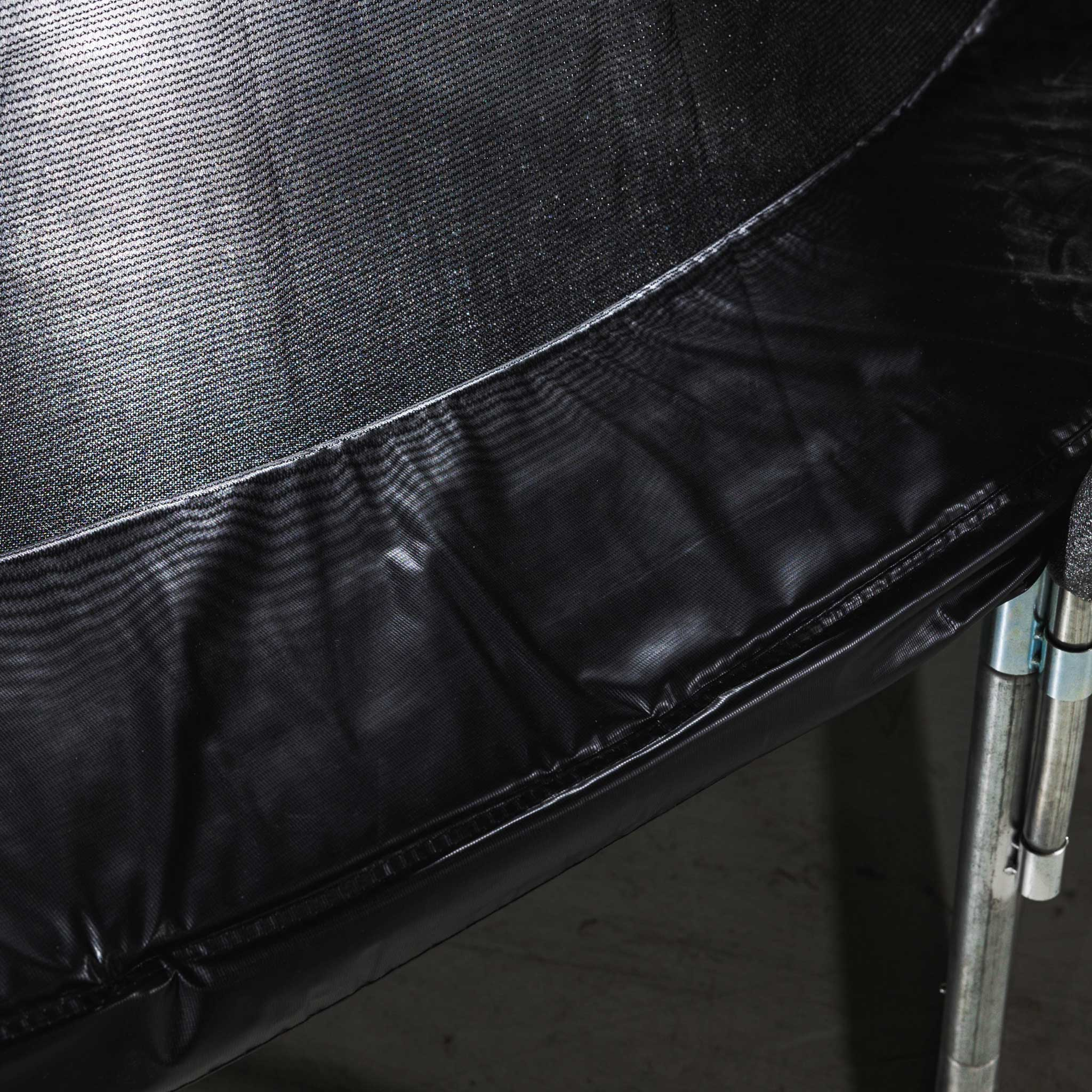 Zbliżenie czarnej siatki trampoliny i ochronnej wyściółki.