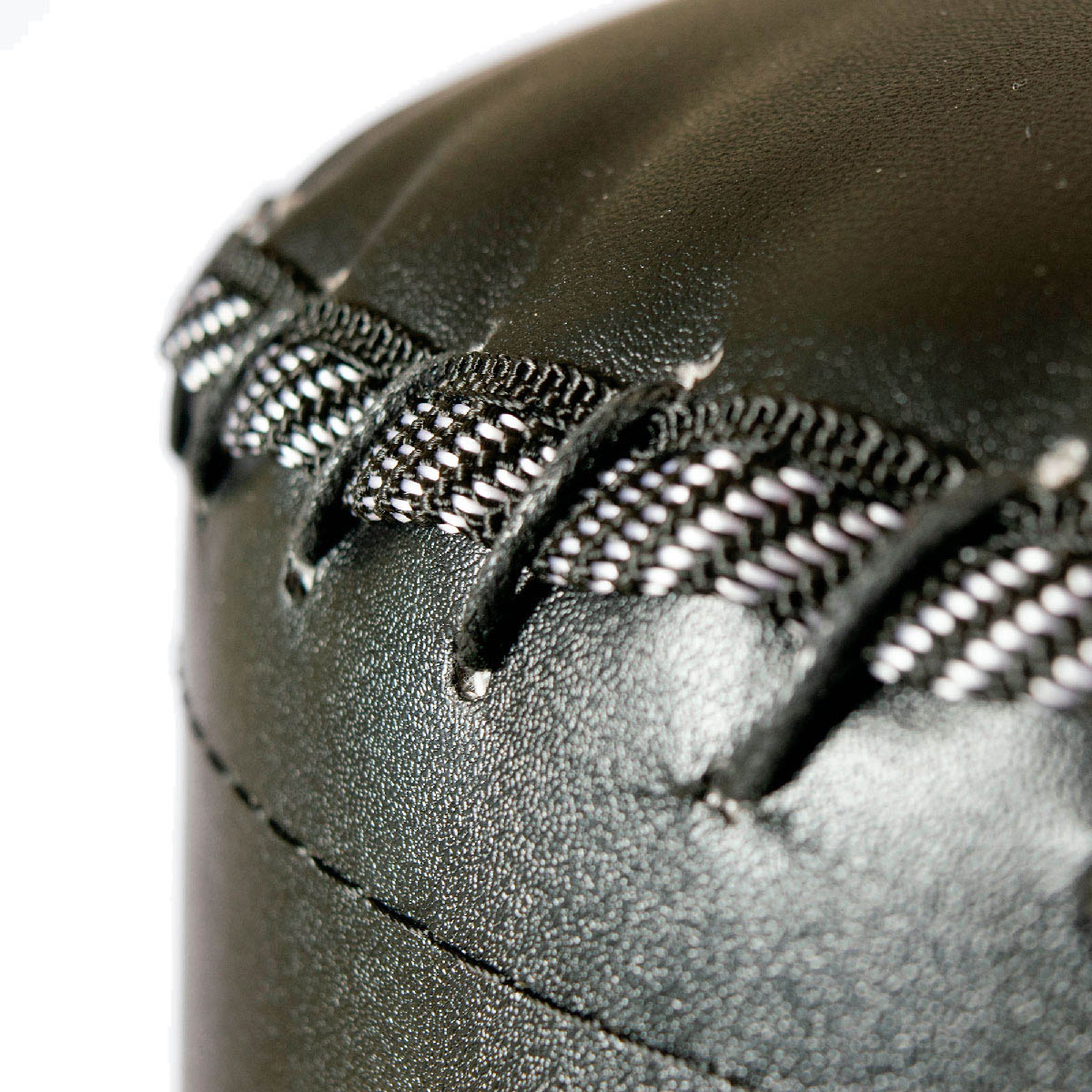 Zbliżenie czarnego skórzanego przedmiotu. Jest zszyty białą nicią, pokazując szczegóły i teksturę.