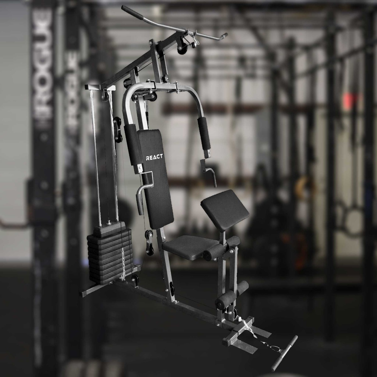 Sprzęt do domowej siłowni z obciążeniami i różnymi stanowiskami, na tle rozmytego tła siłowni.