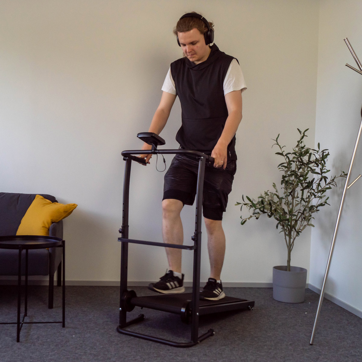 Mężczyzna korzystający z bieżni z poręczą, noszący słuchawki.