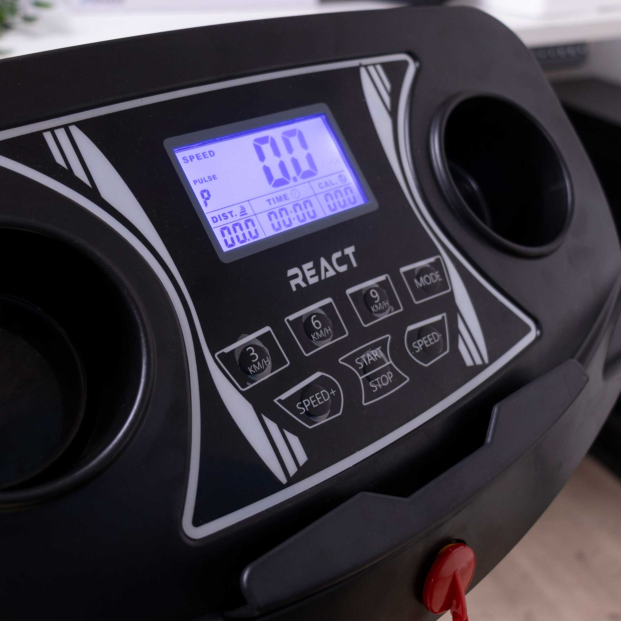 Czarny panel sterowania bieżnią wyświetlający prędkość, puls, czas i dystans. Posiada przyciski.