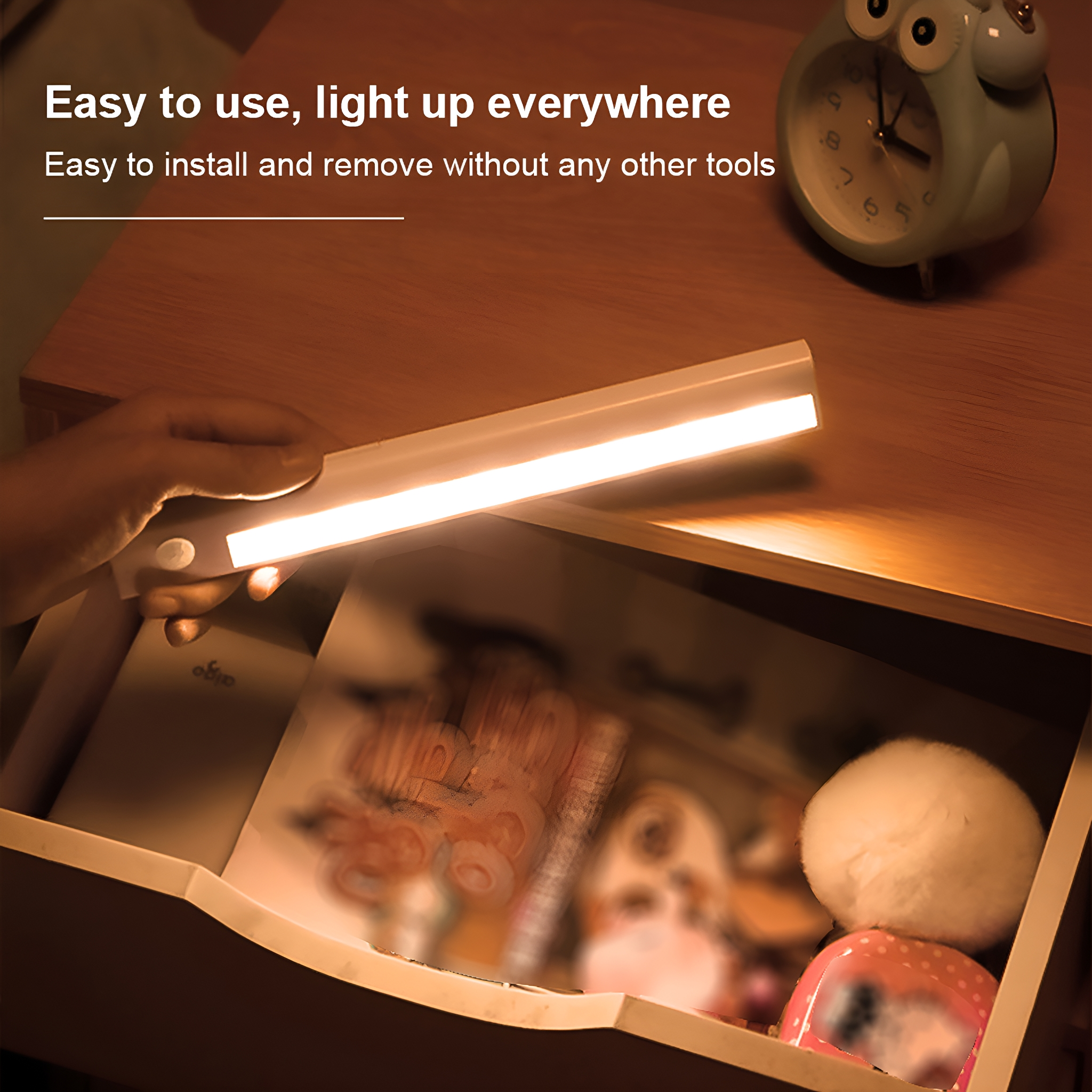 Eine weiße Lichtleiste wird gehalten und beleuchtet eine Schublade mit Inhalt. Das Licht ist an.