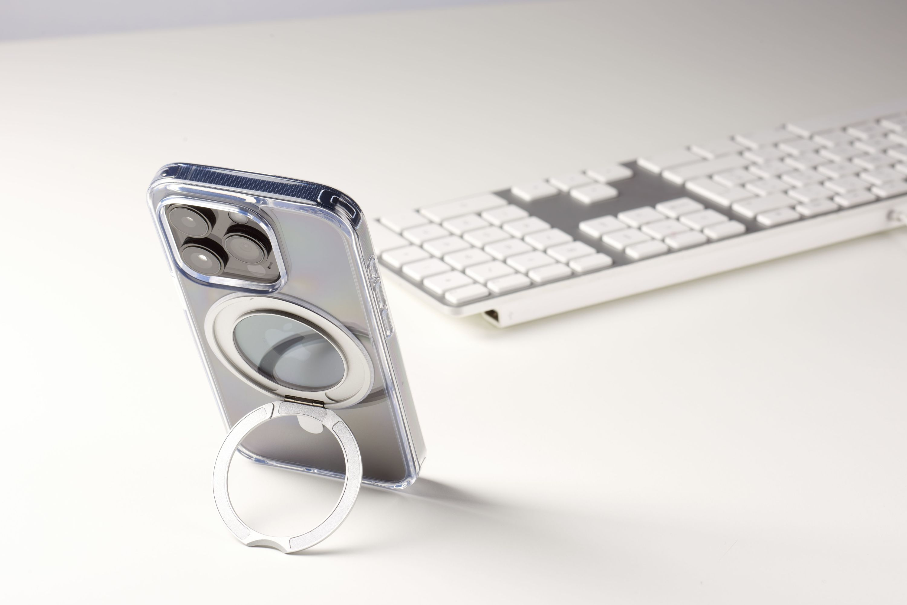 Téléphone dans un étui transparent avec un support de bague. Le téléphone est sur une surface blanche avec un clavier.