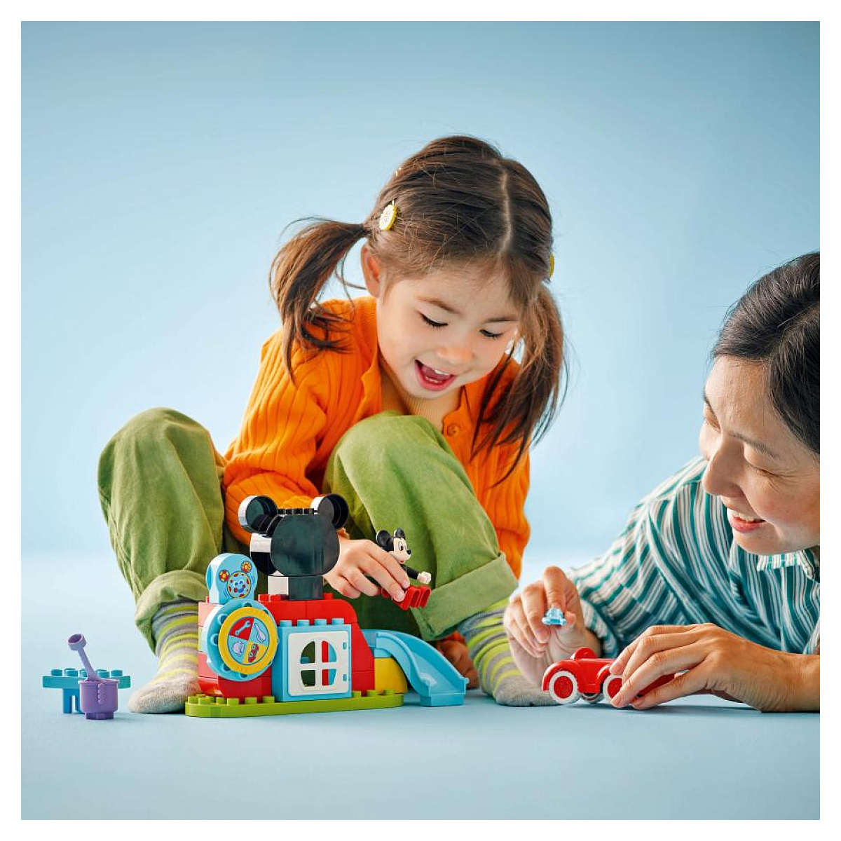 Dziecko i dorosły bawią się klockami LEGO Duplo. Budują zestaw tematyczny z Myszki Miki.