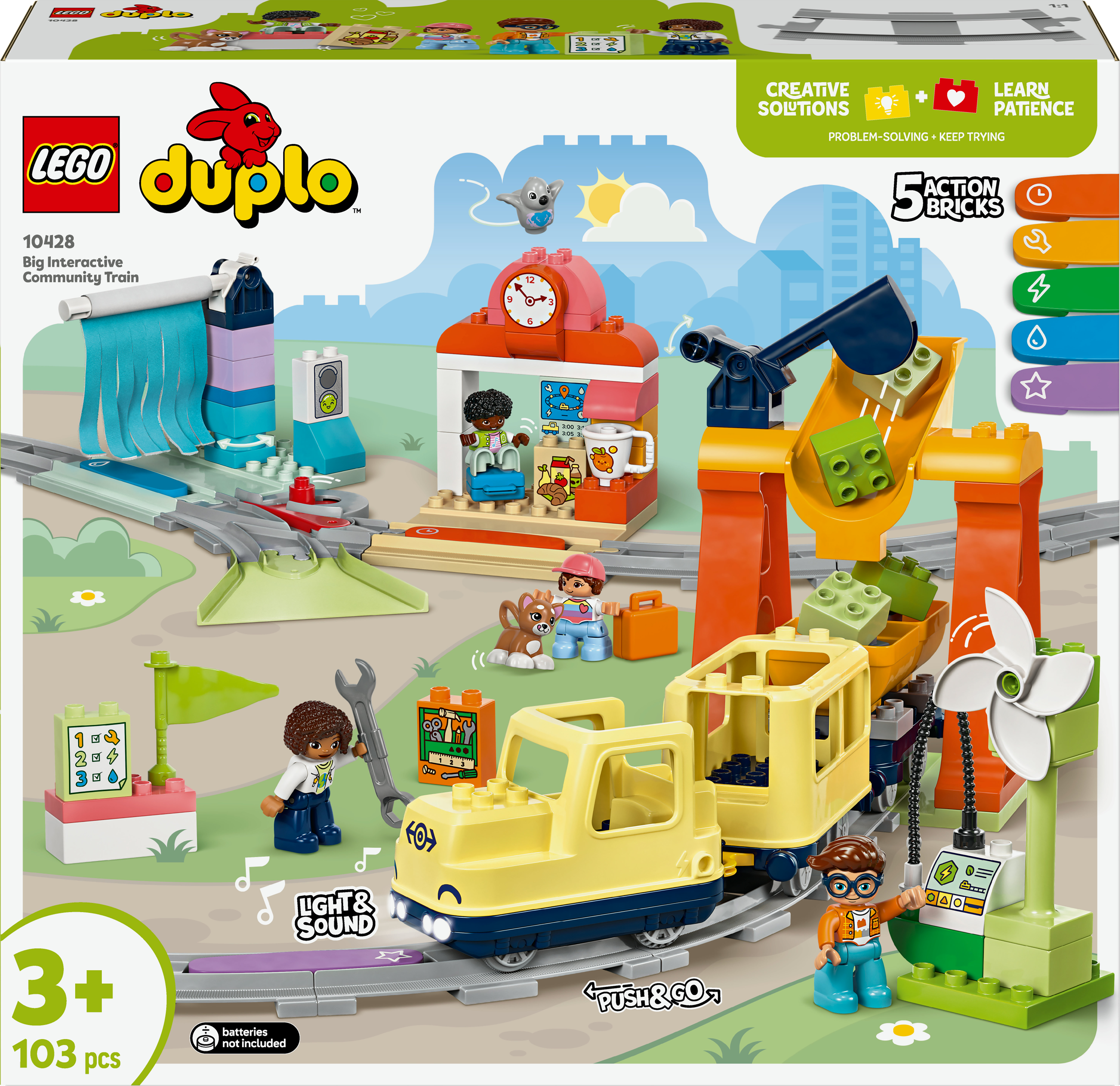 Un tren Lego Duplo amarillo con figuras y edificios. La caja del set es visible. El tren está sobre vías.