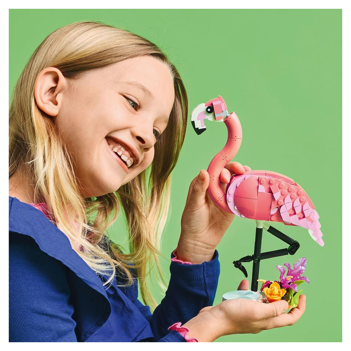 Dziewczyna uśmiecha się i trzyma model Lego flaminga z kwiatami.