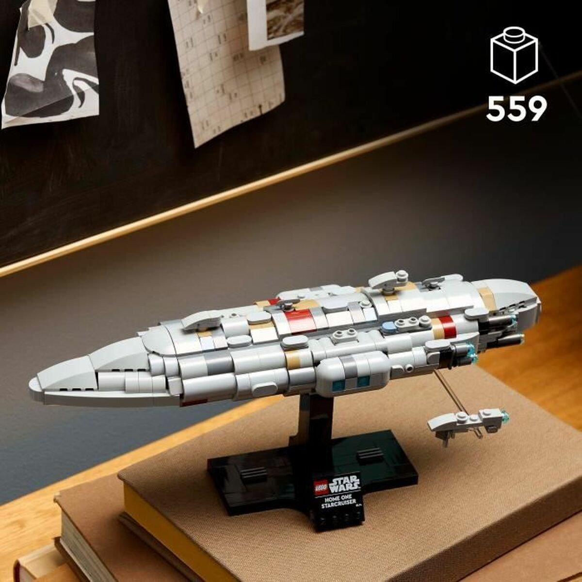 Model Lego Star Wars Home One Star Cruiser. Stoi na podstawce na stosie książek. Ciemne tło z kilkoma kartkami.