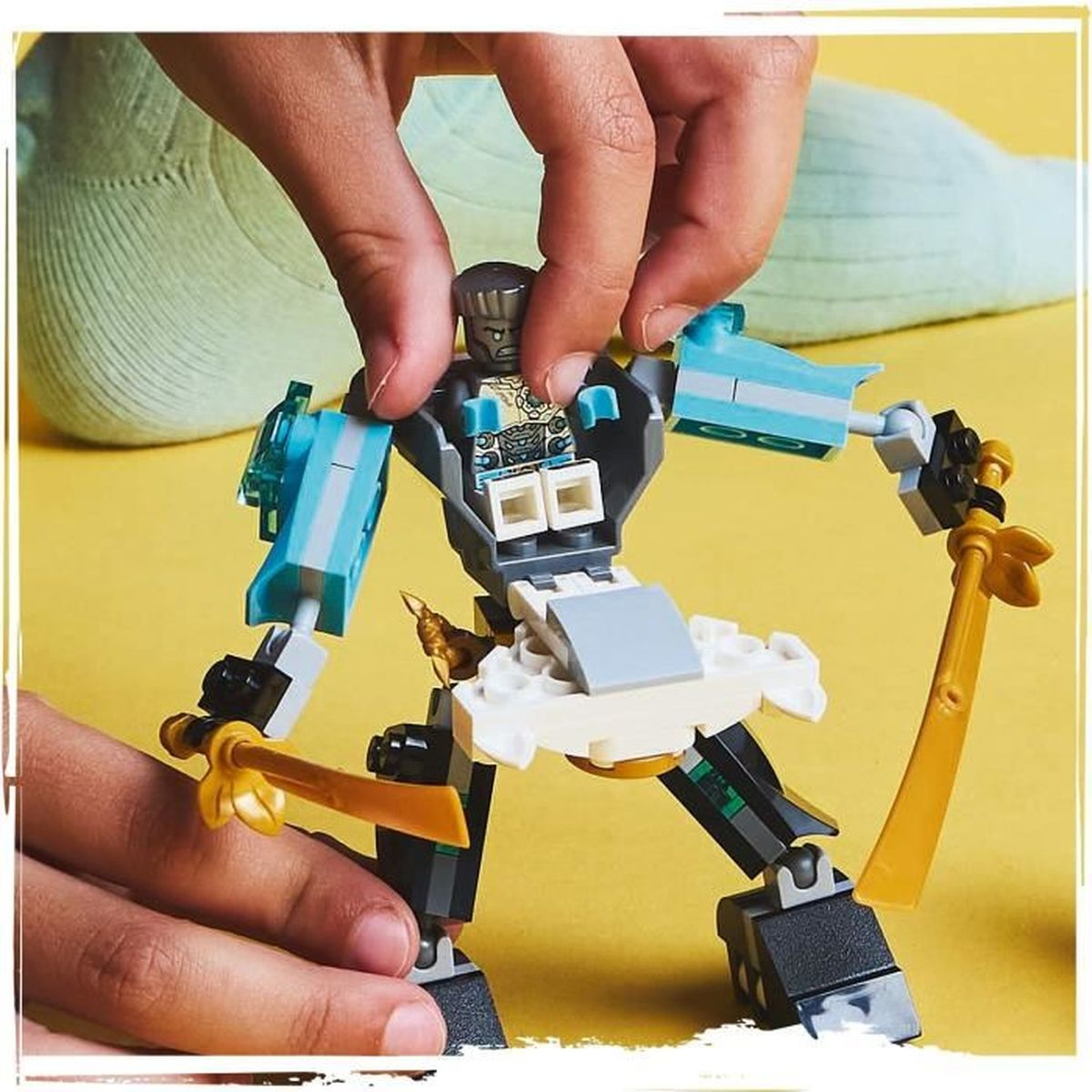 Bir kişi bir LEGO mekiği birleştiriyor. Mek, beyaz bir gövde ve siyah bacaklarla mavi ve altın vurgulara sahip.