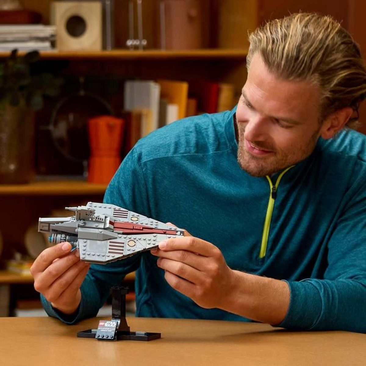 Mężczyzna ogląda model statku kosmicznego LEGO. Uśmiecha się i trzyma model.