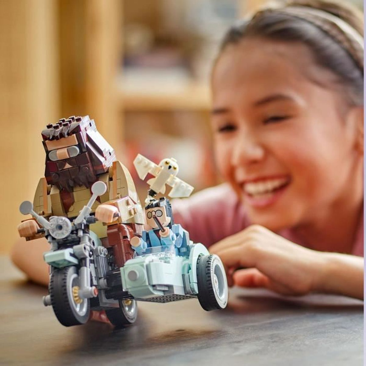 Bir kız, bir motosiklet ve yan araba üzerinde iki figürlü bir Lego setine gülümsüyor.