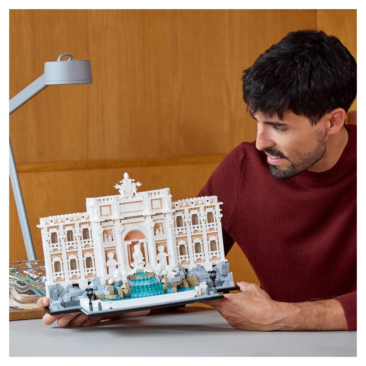 Mężczyzna ogląda model Lego Fontanna di Trevi, trzymając go w rękach. Model jest biały.