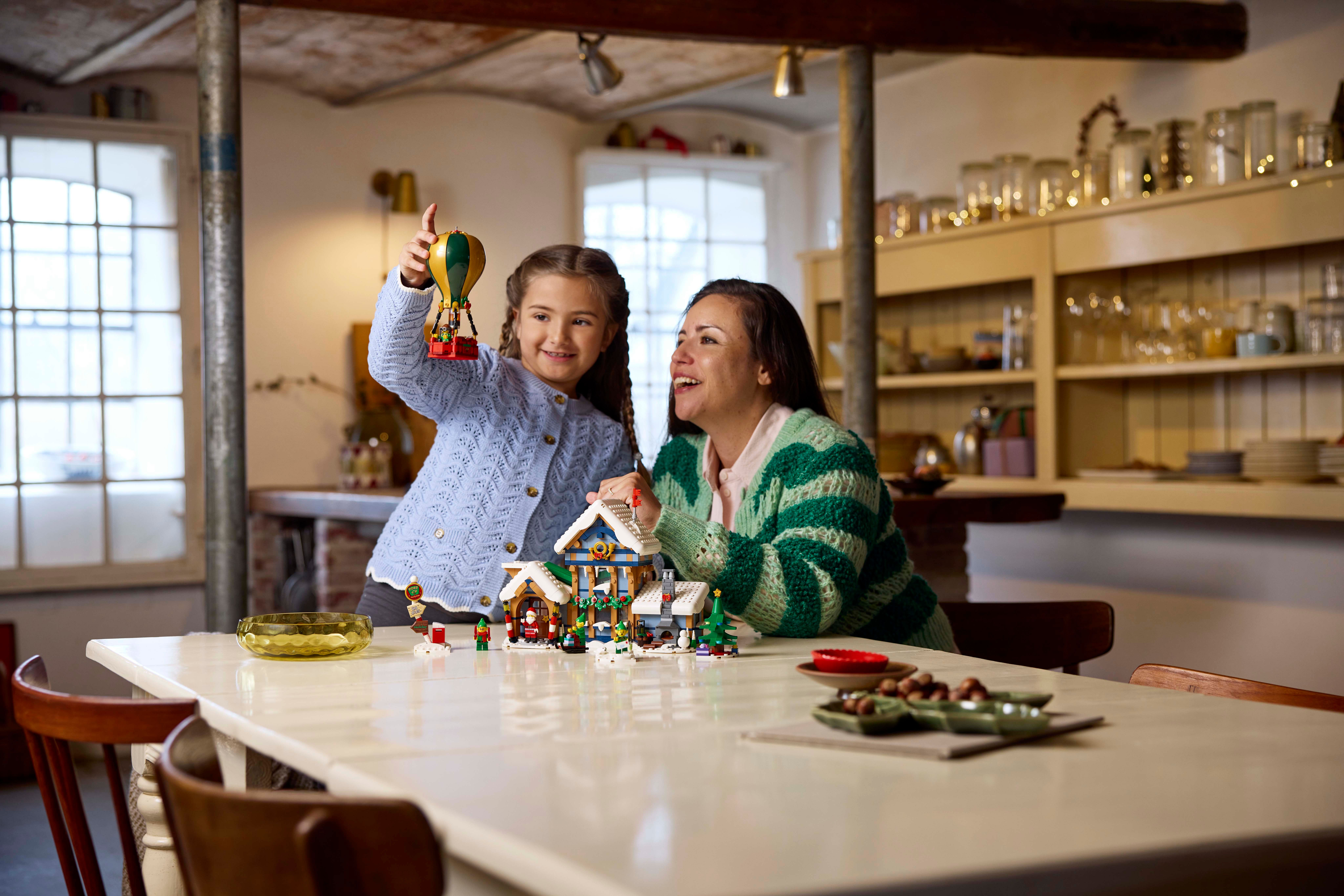 Una donna e una bambina giocano con un set Lego su un tavolo in una stanza luminosa.