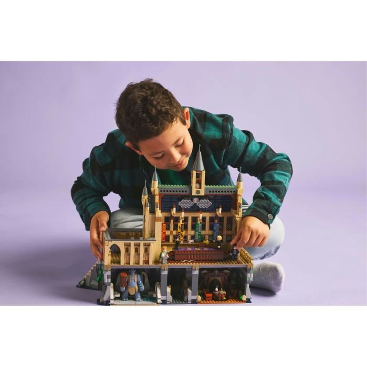 Ein Junge spielt mit einem Lego Hogwarts Set. Er sitzt und interagiert mit dem Modell.