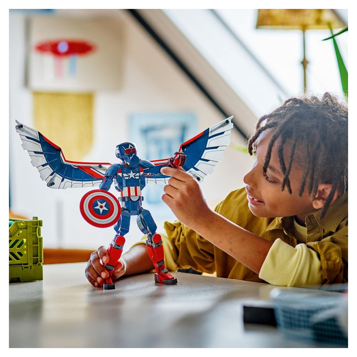 Chłopiec trzymający figurkę Lego Kapitan Ameryka ze skrzydłami i tarczą. Chłopiec się uśmiecha.