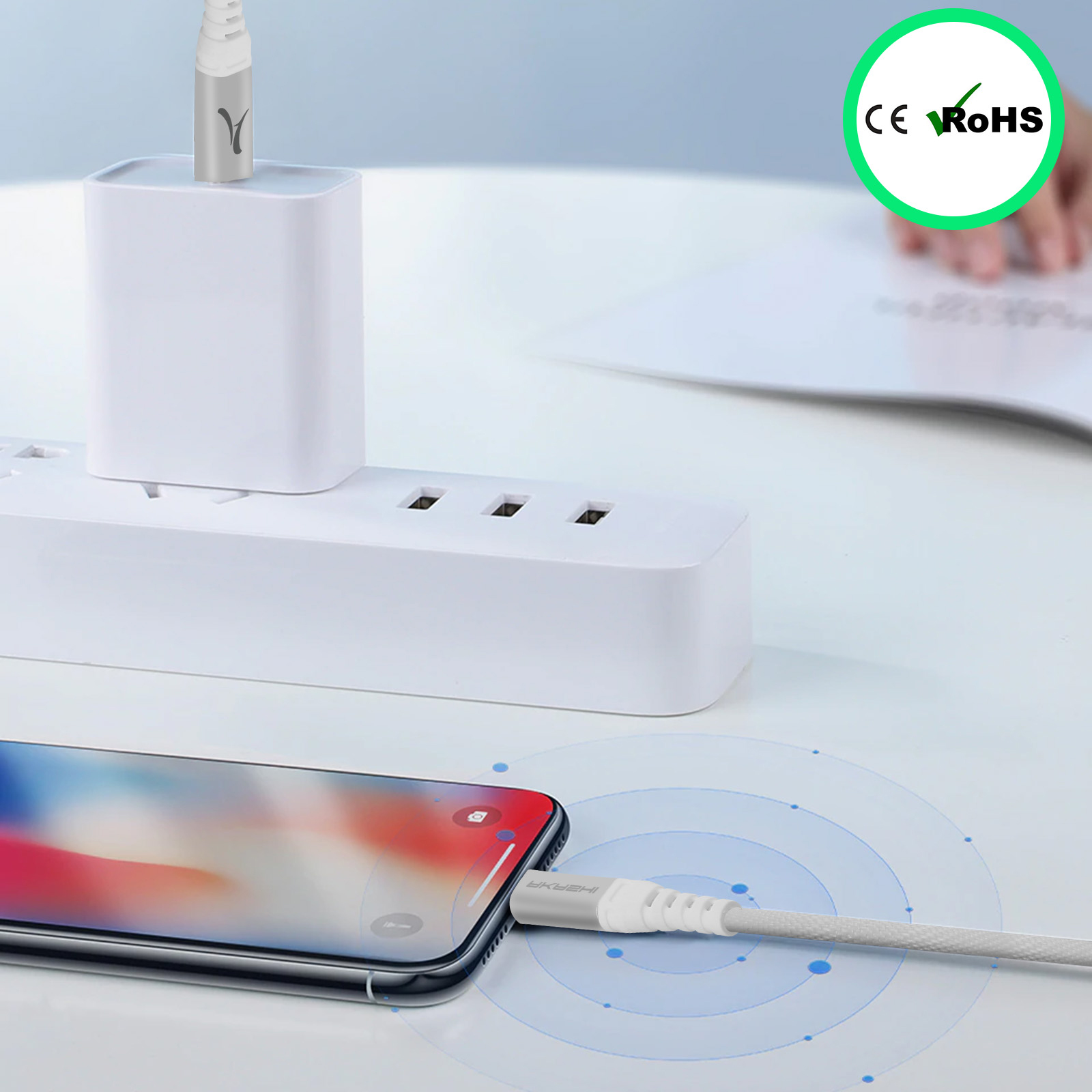 Téléphone en charge avec câble blanc connecté à un chargeur blanc sur une multiprise. Logo CE/ROHS.