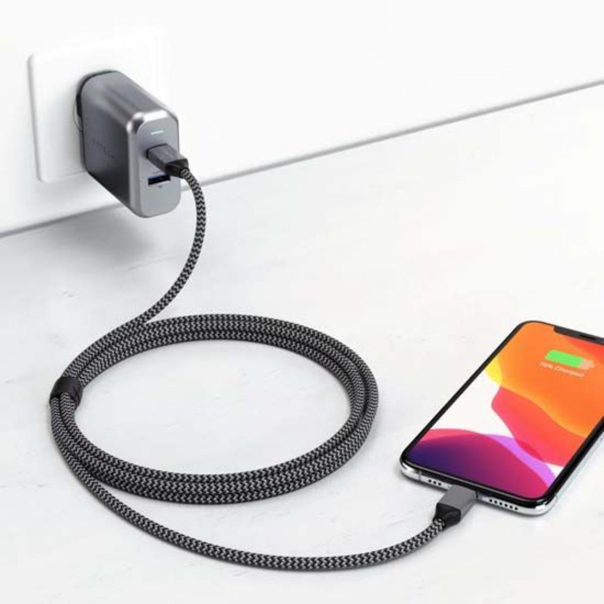 Telefon lädt mit geflochtenem Kabel. Telefon lädt, Stecker an der Wand.