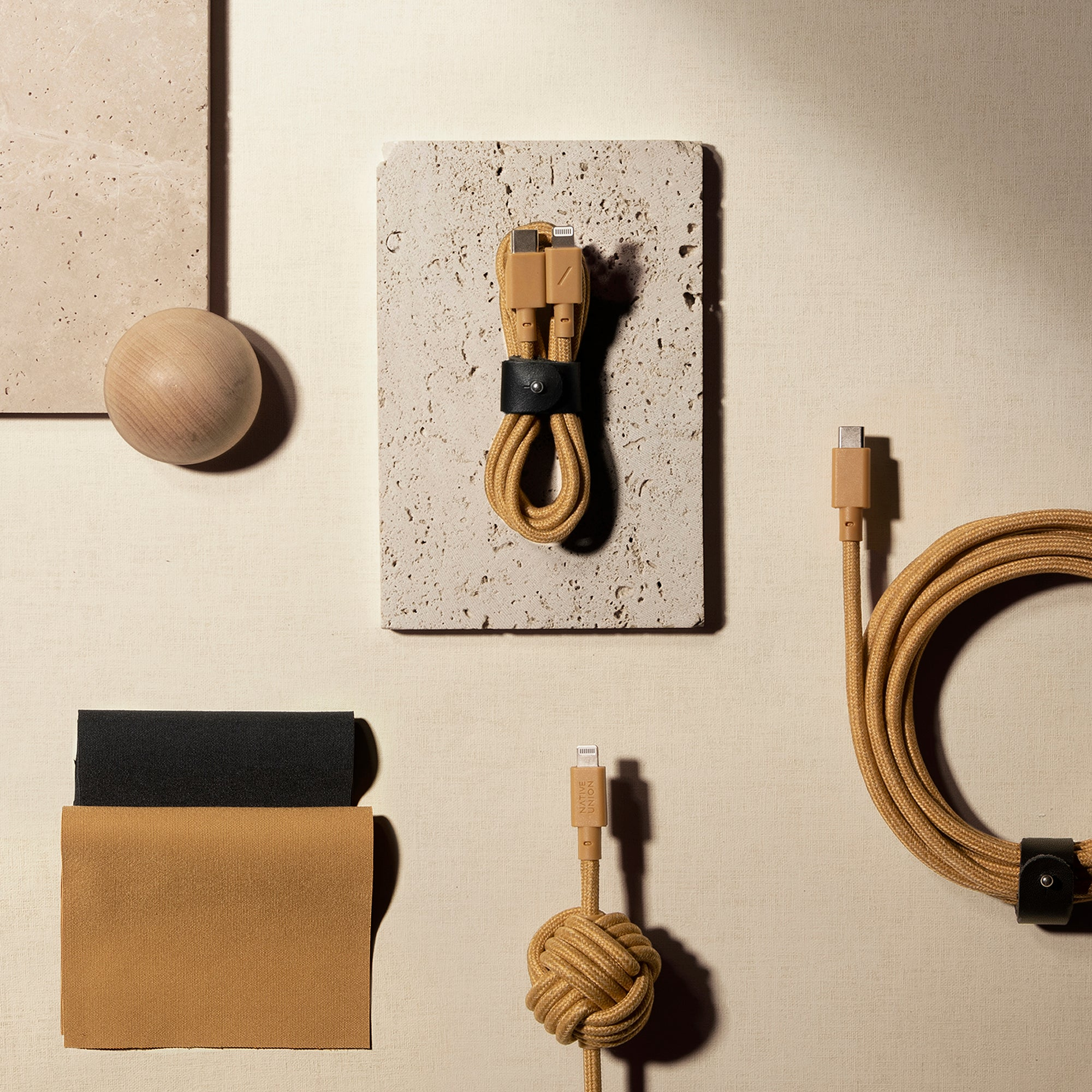 Beige Kabel mit schwarzem Band und Holzkugel auf beigem Untergrund.