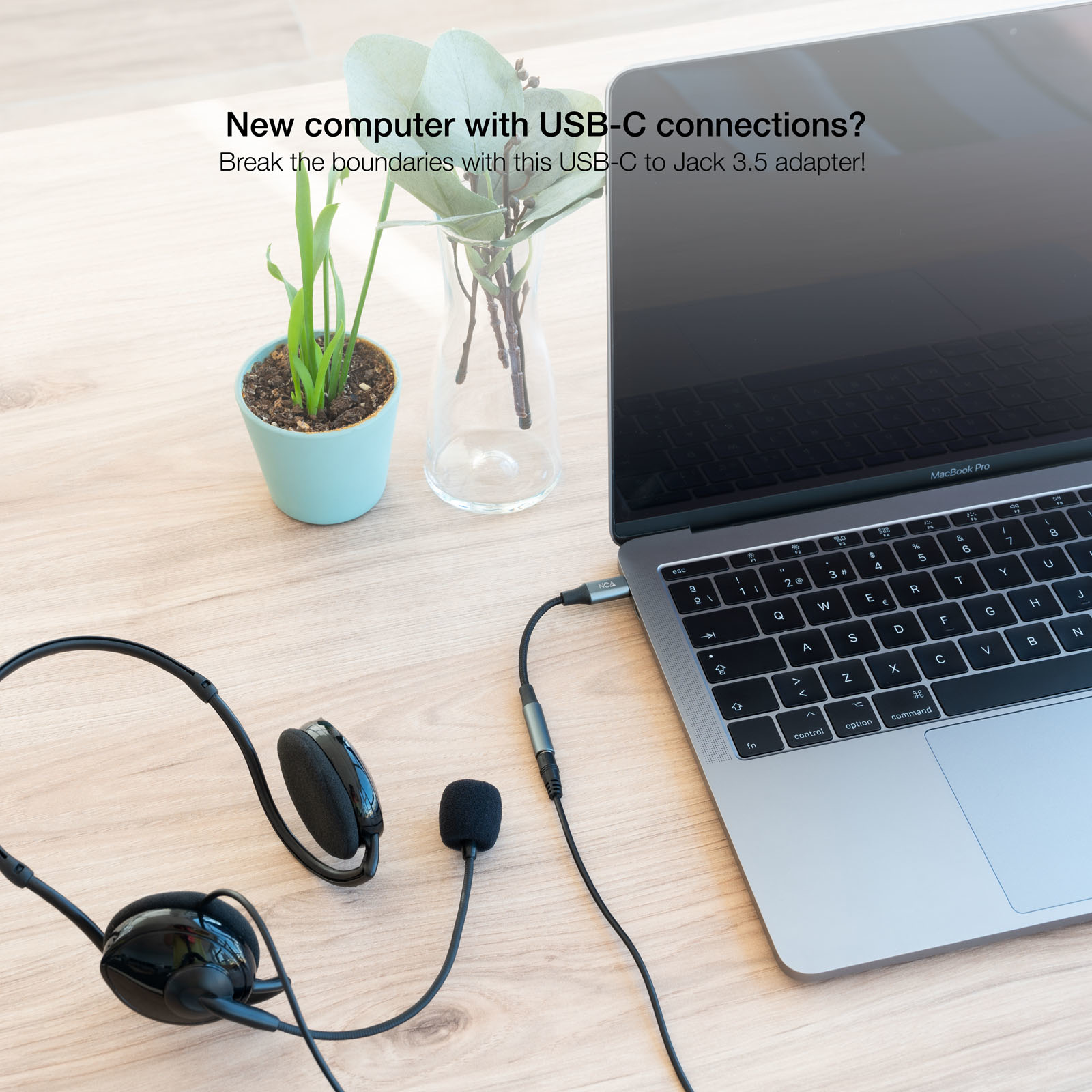 Laptop con adattatore USB-C a jack da 3,5 mm collegato a cuffie e microfono.