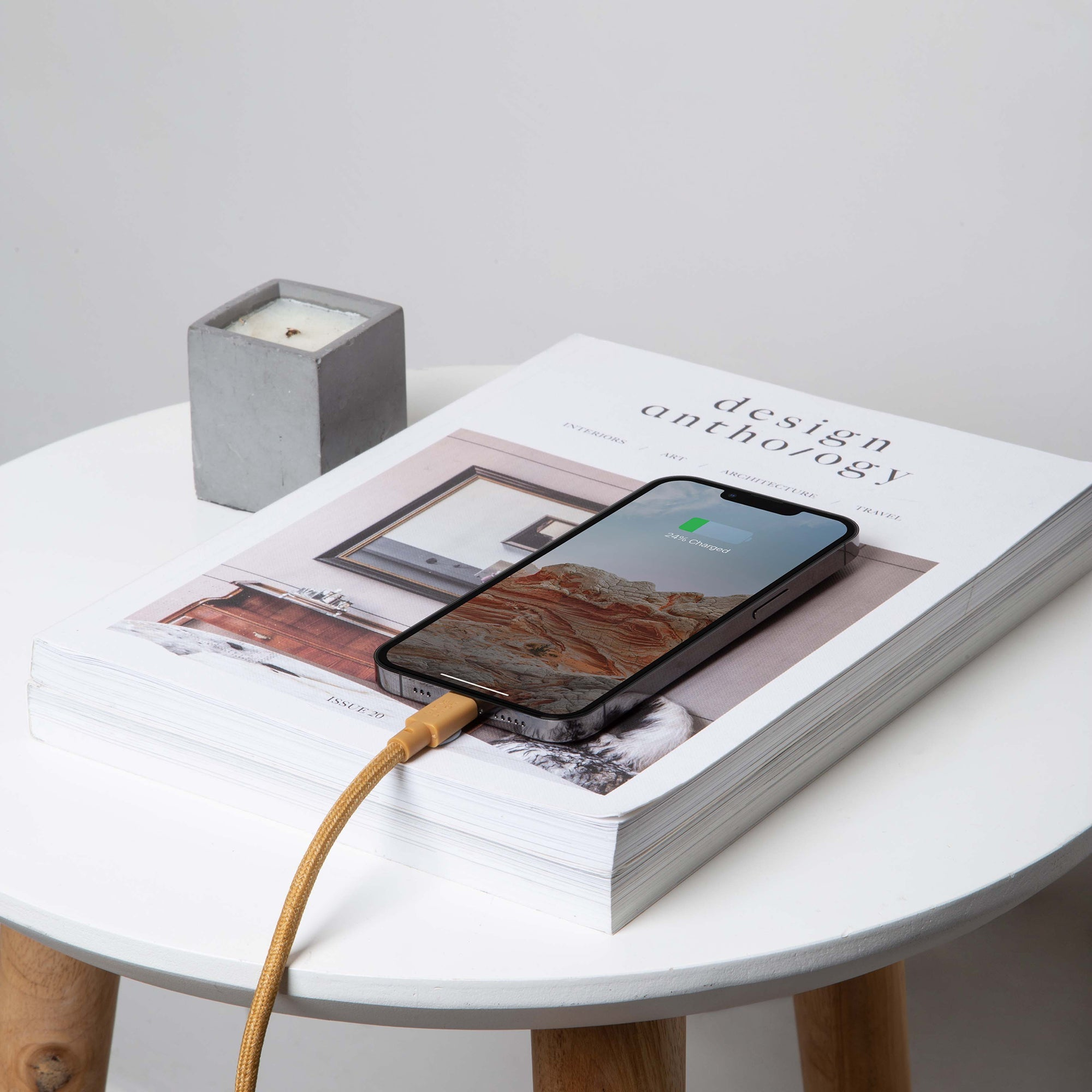 Un telefono in carica su un tavolo, con un cavo e una rivista.