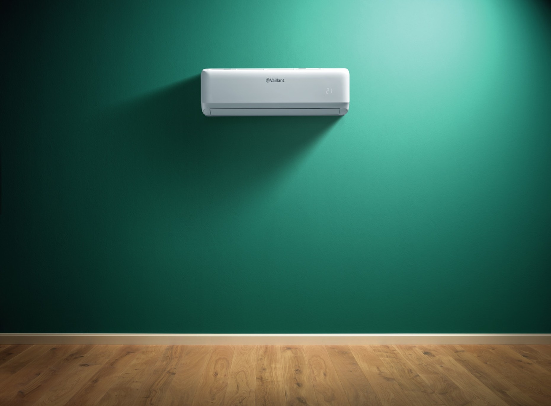 Un condizionatore bianco su un muro verde acqua con pavimento in legno. Il condizionatore ha il marchio Vaillant.