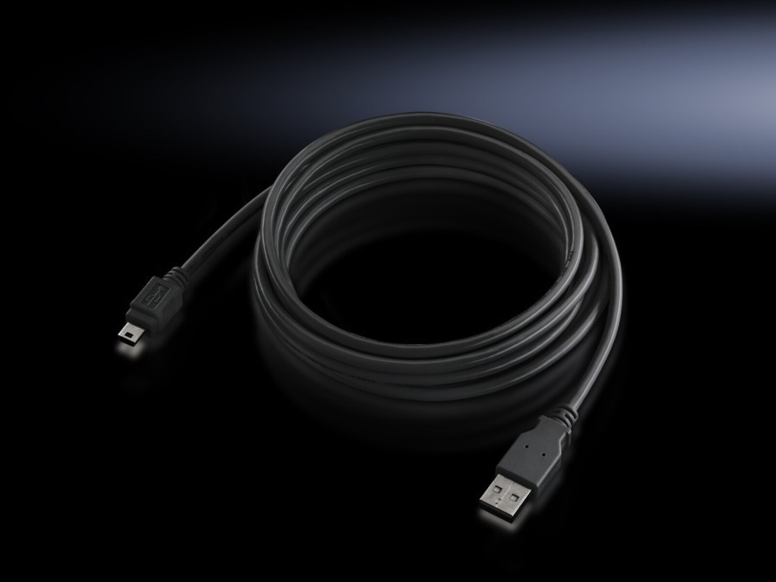 Cavo da USB a micro-USB nero avvolto su una superficie scura. Superficie riflettente, scarsa illuminazione.